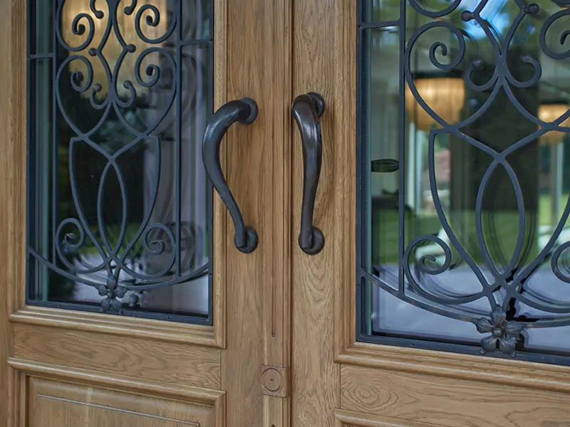 Drzwi zewnętrzne drewniane - metalowe pochwyty i szyby drzwiowe z kutą kratą